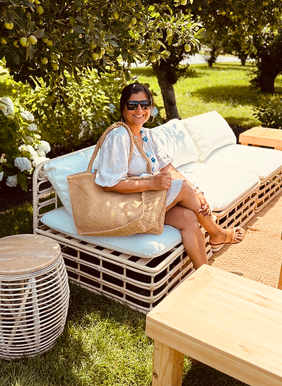 Portrait of Sunita Narma, North Fork style founder and, podcast voice and co-host behind NOFO Live. Women-led boutique owner of NOFO Style holding raffia bag on location in a vineyard.