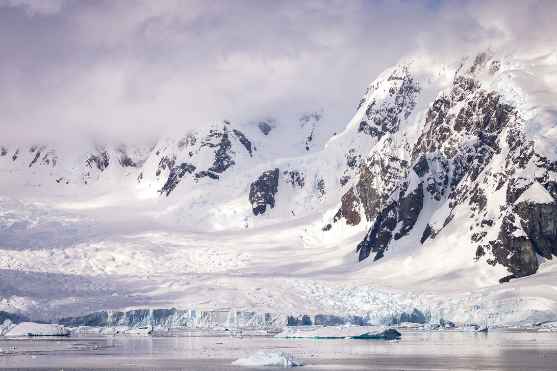 Skontorp Cove is surrounded by steep, rugged mountains often capped with snow and ice, creating a dramatic, isolated landscape. Antarctica. Julie Edgley
