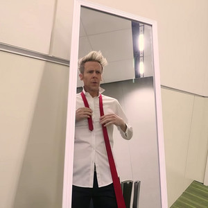Ryan Joyce standing in front of a mirror doing up his tie