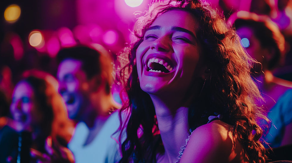 A lady laughing hilariously in a full theatre audience