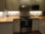 Picture of a kitchen with white cabinets, butcher block countertop, and stainless steel appliances