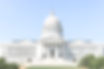 front facing view of the exterior of the Missouri Capitol building with lush green trees and a bright blue sky