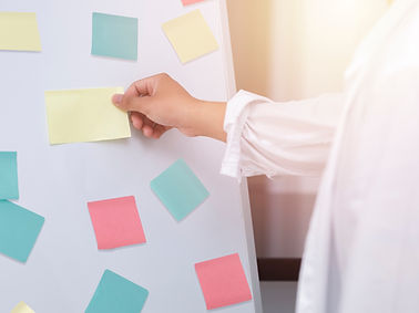 Eine Person klebt bunte Postit-Zettel an einen Flipchart.