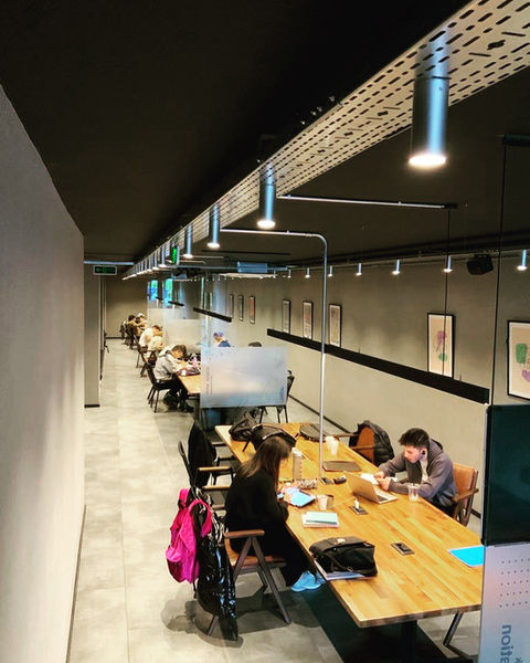 Çalışanların uzun masada çalıştığı modern ortak çalışma alanı