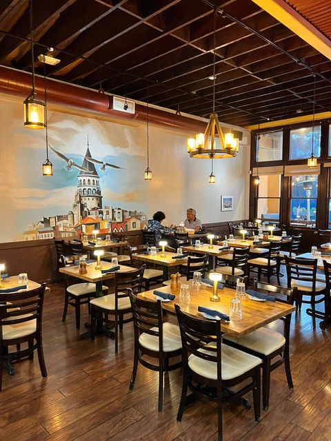 İstanbul manzaralı aydınlık restoranın ahşap masa ve sandalyeleriyle dolu yemek salonu
