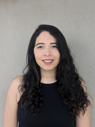 Cindy Stephenson, LPC at Empower Psychotherapy, smiling in front of a light gray background with long curly hair and a welcoming expression