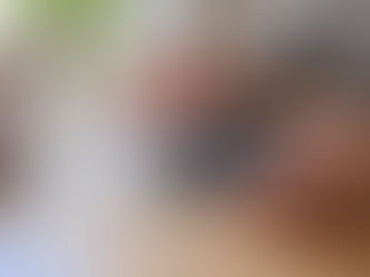 Adult hands wipe the rear camera lenses of an unbranded phone with a soft cloth on a wooden table.