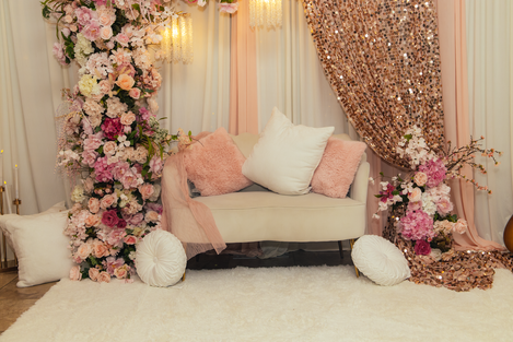 a white couch surrounded by pink flowers and white pillows