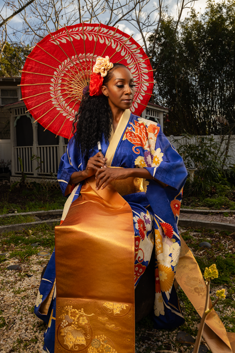a woman in a blue and gold kimono holding a red umbrella