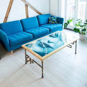 Blue Dame coffee table with original graffiti by Rasmus Balstrøm. A woman's face framed by oak and legs of brass and black pipes