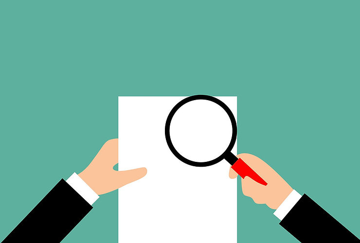person with magnifying glass over piece of paper to demonstrate food safety due diligence meaning