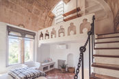 Bright bedroom with traditional stone walls and wooden staircase in a Mallorca finca