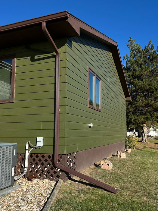 Brown finished 6-inch seamless gutter installation with matching downspouts on a Black Hills residence.