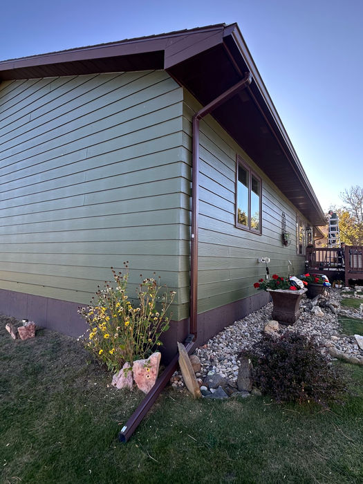 Brown finished 6-inch seamless gutter installation with matching downspouts on a Black Hills residence.