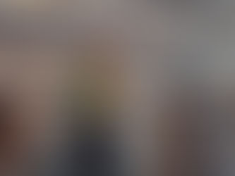 Woman in green jacket and black skirt stands at Colosseum railing, looking over ancient ruins. 