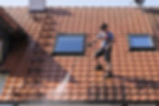 A professional worker cleaning roof tiles using a jet washer
