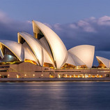 Opéra de Sydney avec ses toits blancs en forme de voiles au bord de l’eau.