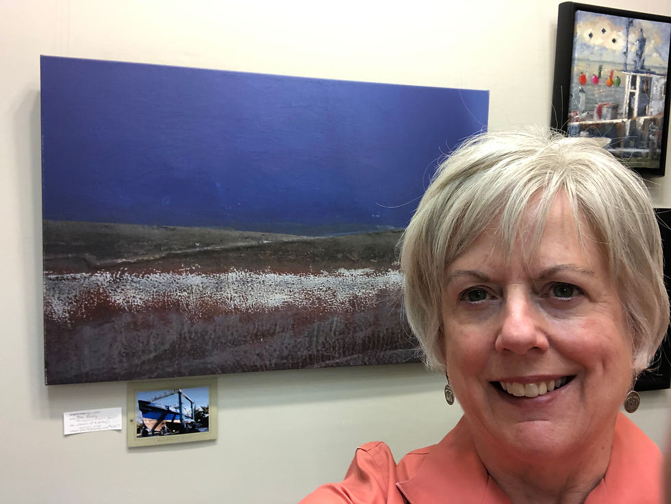 White woman with blonde hair in front of photographic abstract of a blue, rust, and white boat hull