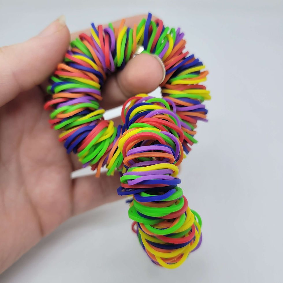 Hand holding colorful, twisted rubber bands in various hues against a plain white background, creating a playful and vibrant mood.