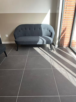Photo d'un sol de carrelage gris antracite. Espace de bureau avec canapés, lumière naturelle et briques toulousaines.