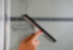 Person using squeegee to dry shower screen door and prevent limescale
