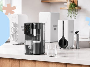 Waterdrop water filter products displayed on a modern kitchen countertop, including countertop and under-sink systems with glass of clear filtered water.