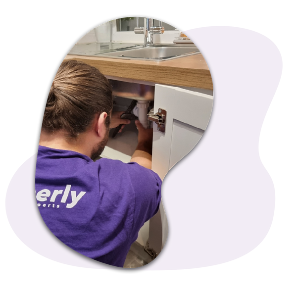 plumber under sink fixing leaking waste pipe