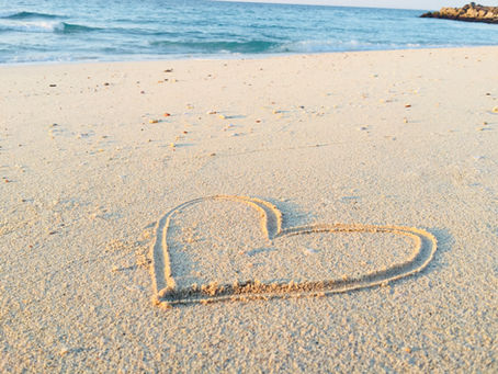 A heart drawn on a white sand beach.