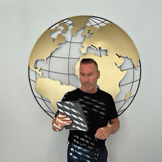 Eirik Moseng standing in front of a metal globe with a gold world map, looking at an iPad, symbolising innovation and digital transformation in the HVAC industry