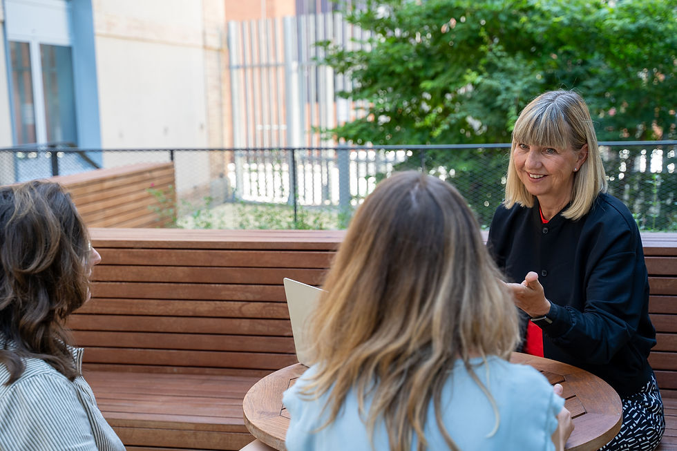 Birgit with the other Wayfinder Summit attendees having a conversation at a wooden table outdoors, surrounded by greenery.