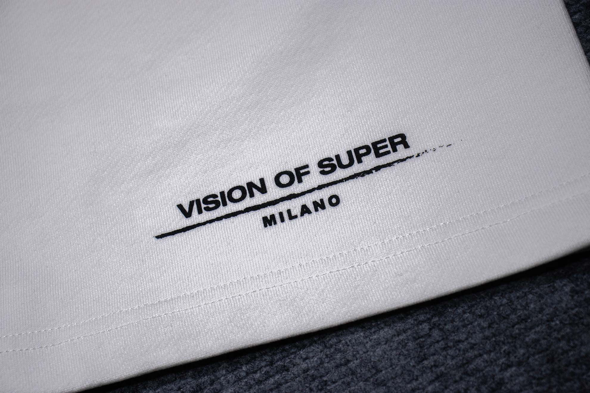 Vải trắng in logo "VISION OF SUPER MILANO" trên áo.