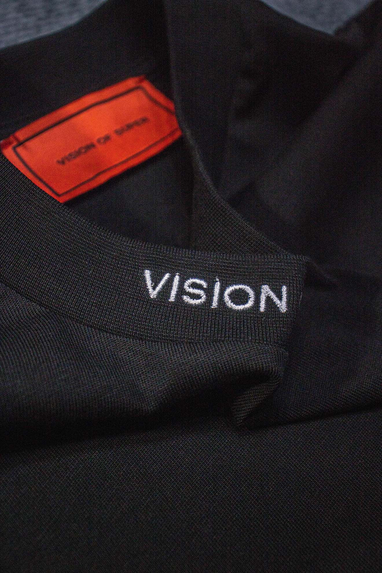 Áo phông đen, nhãn cam VISION OF SUPER chi tiết rõ nét.
