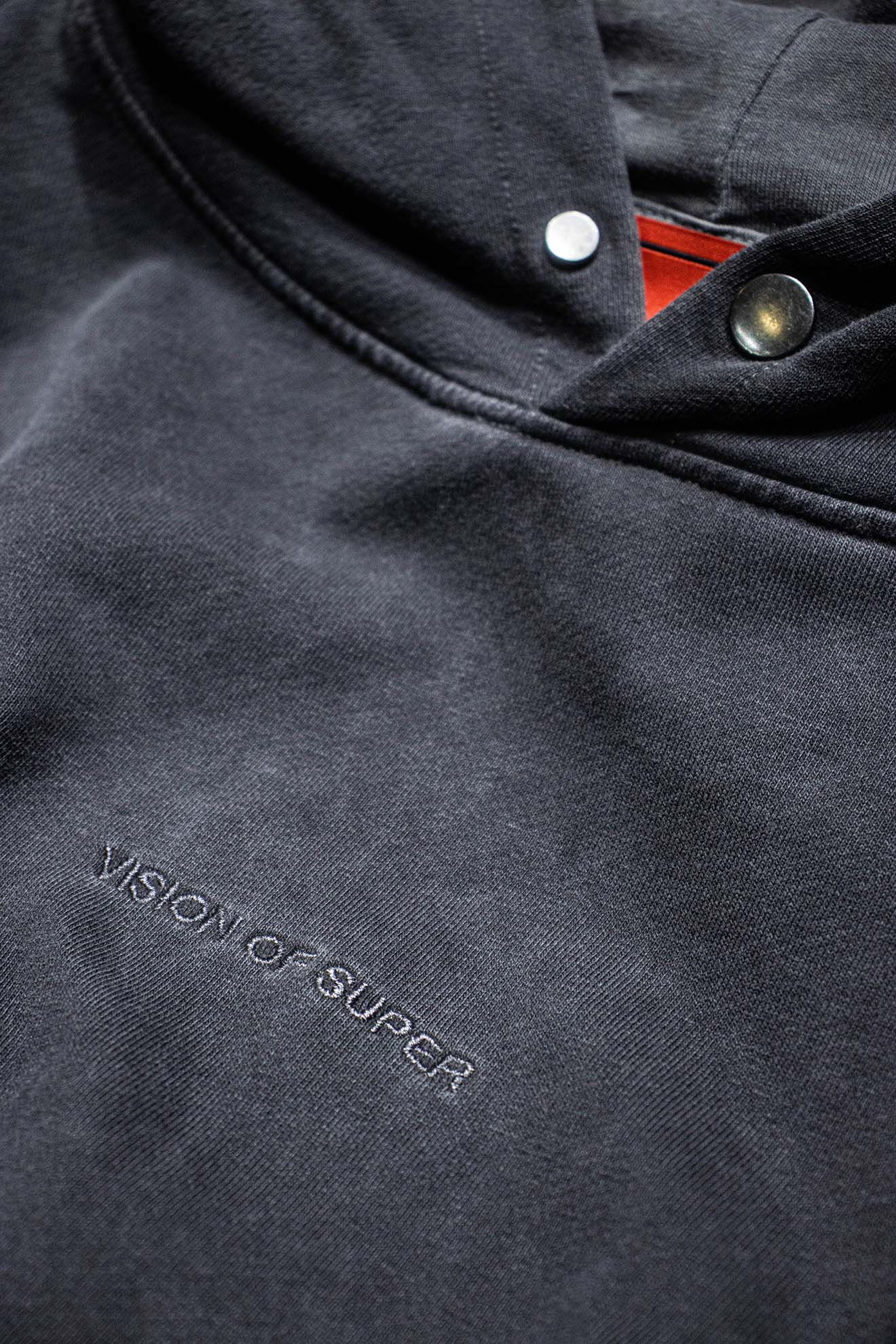 Áo hoodie đen bạc màu thêu chữ "VISION OF SUPER" rõ ràng.