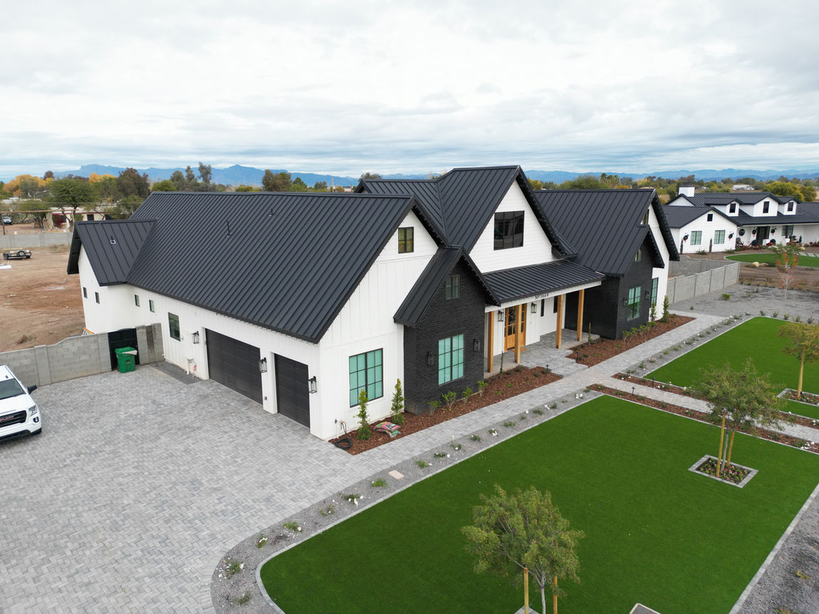 Drone picture of a modern farmhouse custom home design, black sheet metal roof, board and batten