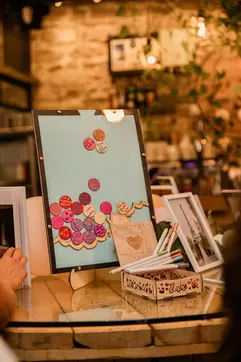 A creative "guest book" display where colorful signed wooden hearts are dropped into a light blue frame.
