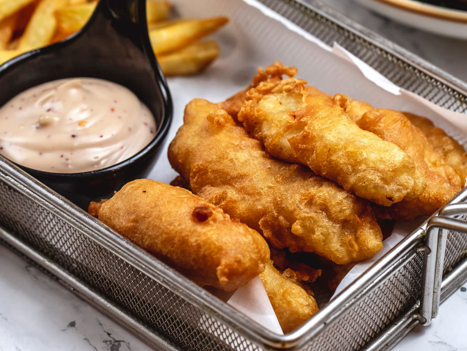 Golden fried fish in a basket with dipping sauce