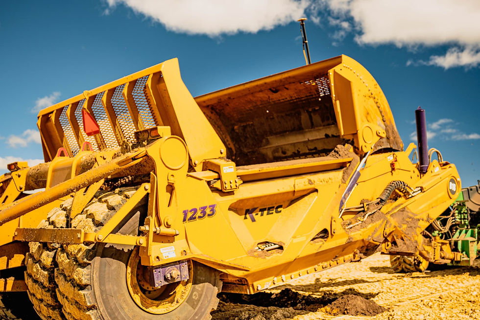 Yellow K-TEC earthmover with the number 1233 against a blue sky.