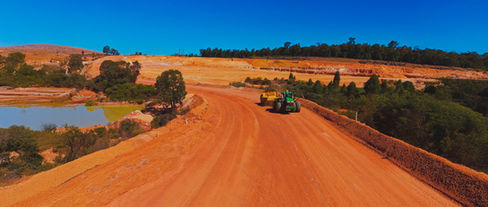 Scraper K-tec being hauled by a wheeled John Deer tractor on a mine site