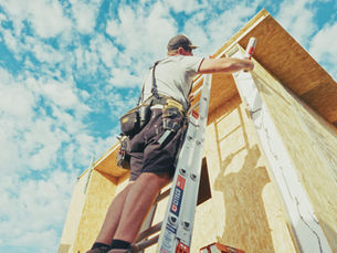 Builder on a ladder installing structural insulated panels on a new home construction site in Western Australia, SIPs construction owner-builder