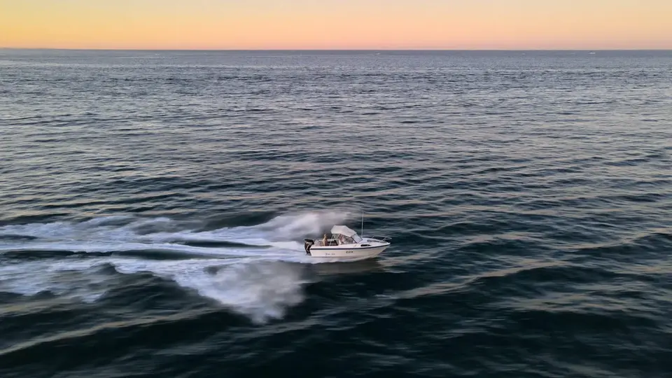Boat speeding on ocean water at sunset