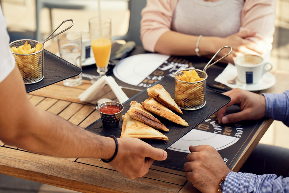 Waiter serving sandwiches and fries to diners outdoors