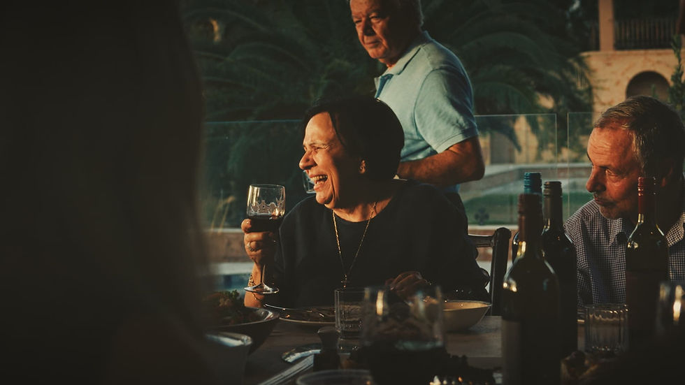 Woman laughing, holding a glass of wine at an outdoor gathering