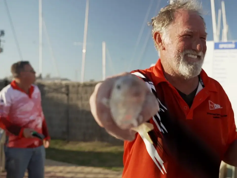 Smiling man holding a racing pigeon at an outdoor event