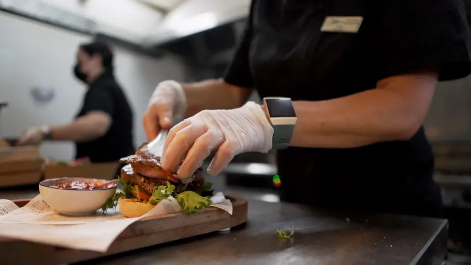 Chef assembling a burger in a kitchen