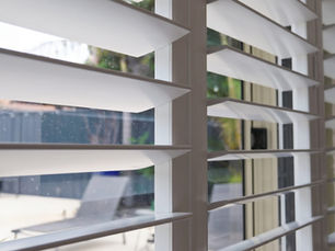 Aluminium plantation shutters with white louvres and grey frame installed on exterior window, Perth home