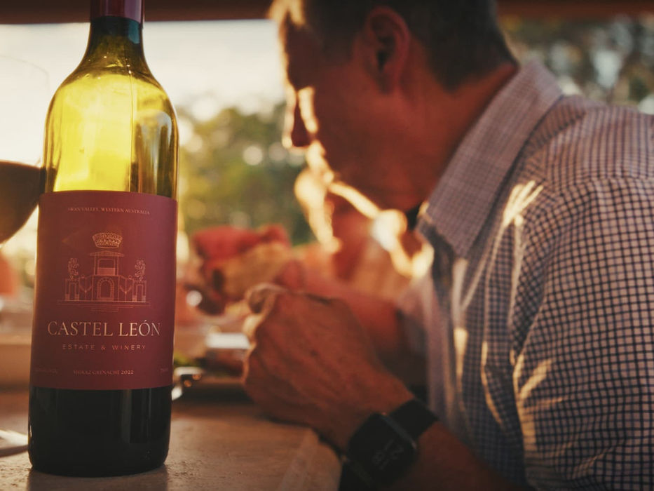 CASTEL LEON red wine bottle and glass, with people dining