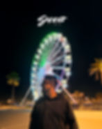 rueda de la fortuna de fondo y al frent eun joven mirando ahcia la izquierda