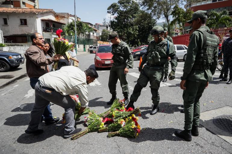 Militares patean las ofrendas florales que personas llevaron a la entrada del Comando General de la Armada Bolivariana este martes en honor a Rafael Acosta Arévalo, en Caracas (Venezuela). Foto: Rayner Peña R. / EFE