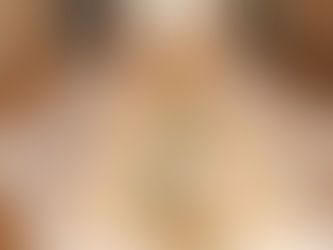 Elegant banquet table set with white chairs, gold plates, cream napkins, and floral centerpieces in a warmly lit room.