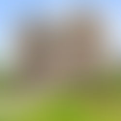 Historic brick building with pointed roofs, large windows, and lush gardens. Sky is clear blue. Address "3121" visible on door.